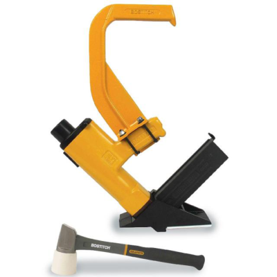 A yellow flooring nailer with a black magazine and a mallet with a white rubber head isolated on a white background.