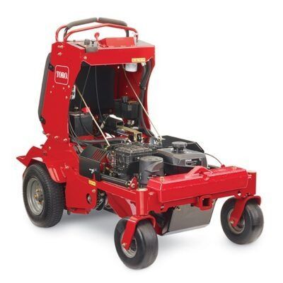 A red Toro stand-on commercial lawn mower viewed from the front, showing the open engine bay and four black wheels.