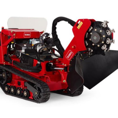 A red Toro tracked stump grinder with a circular cutting blade, isolated against a white background.