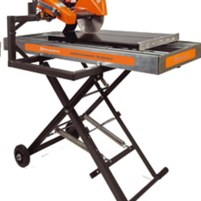 An orange and grey Husqvarna masonry saw with a diamond blade, mounted on a mobile, black X-frame metal stand with wheels.