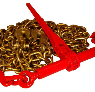 A red metal lever-style chain binder lying across a coiled pile of gold-colored steel transport chain with hooks.