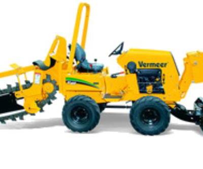 A bright yellow Vermeer trenching machine with large black tires, parked on a white background.