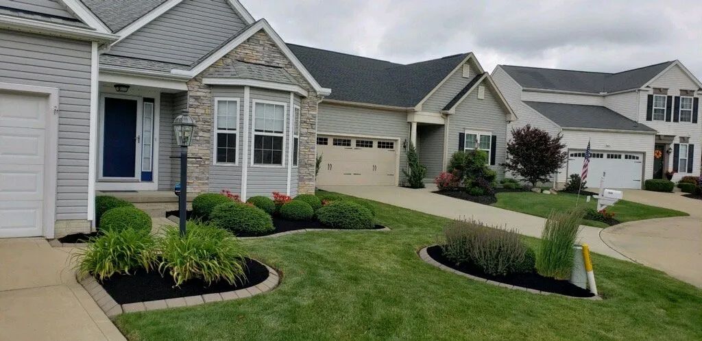 Row of houses with manicured lawns and landscaping under a cloudy sky.