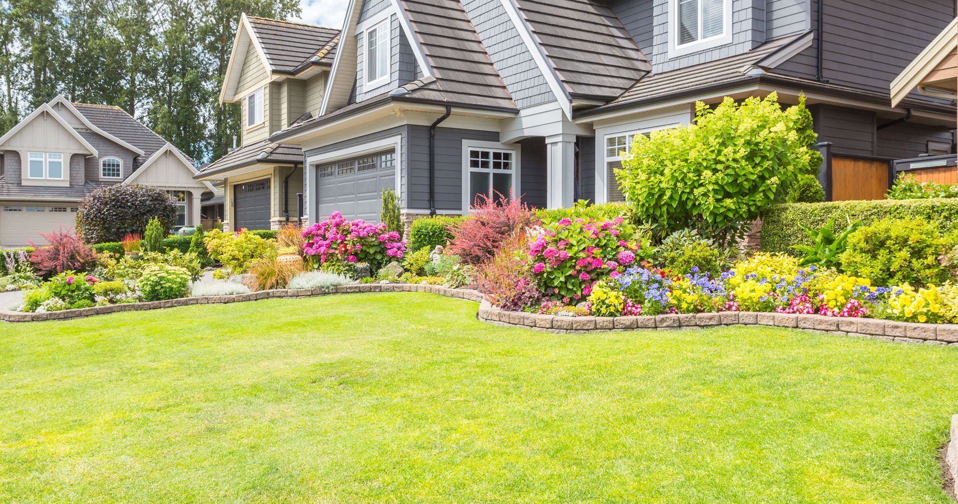 Houses with lush green lawns and colorful flower beds.