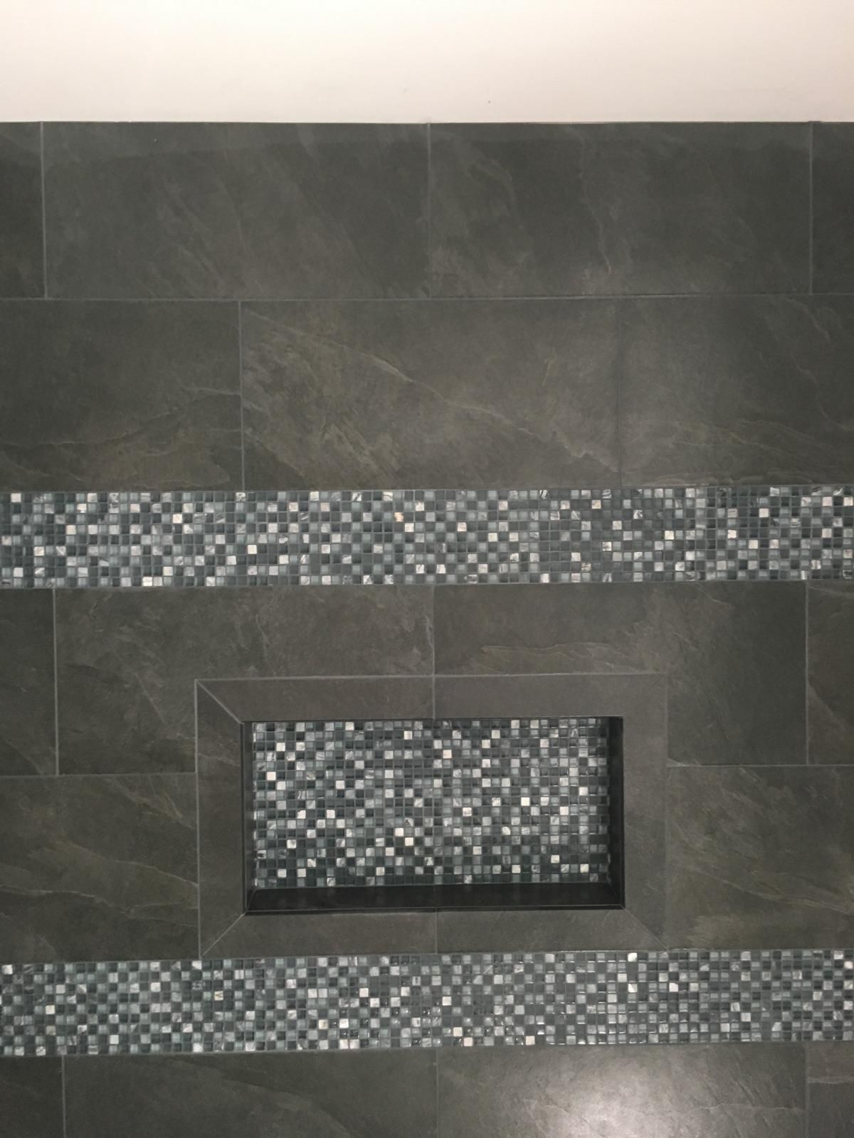 A black tile wall with a mosaic border