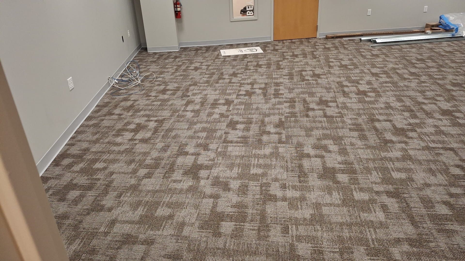 A large room with a carpeted floor and a door.