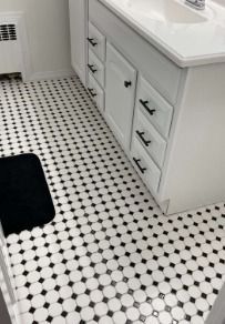 A modern white bathroom vanity with black hardware sits on classic white and black octagonal floor tiles.