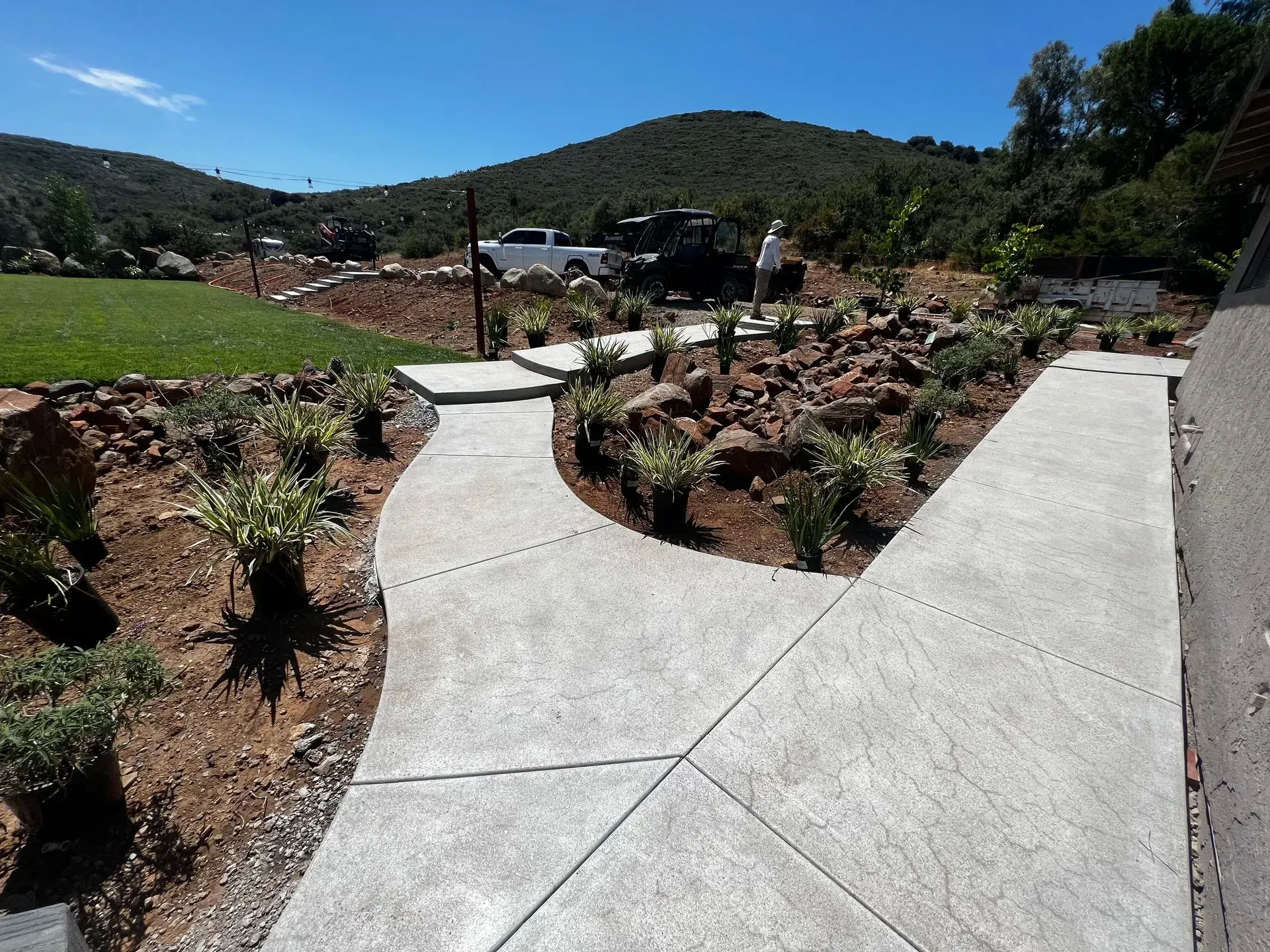 Concrete walkways split, surrounded by landscaping, with a mountain backdrop.