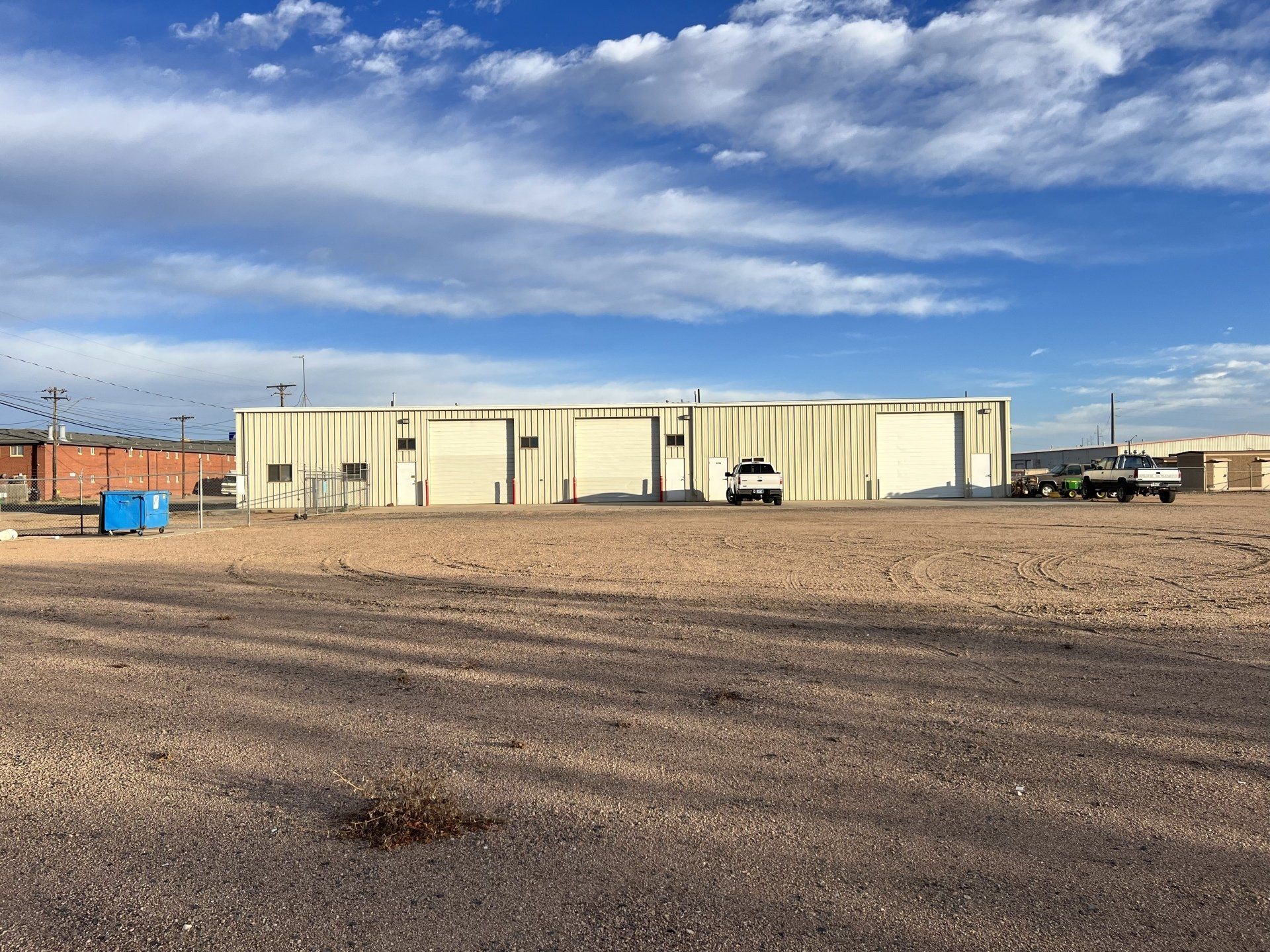 A large building with a lot of doors is sitting in the middle of a dirt field.