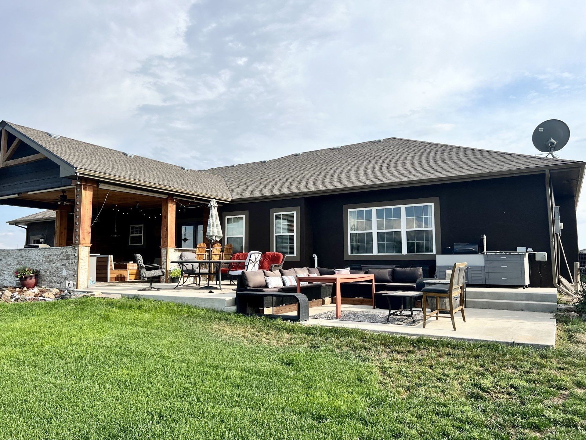 A large black house with a patio area in front of it.