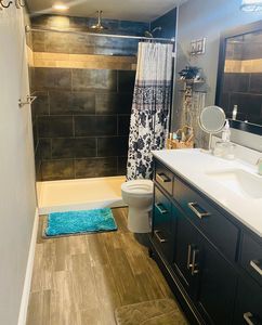 A bathroom with a toilet , sink , mirror and shower.