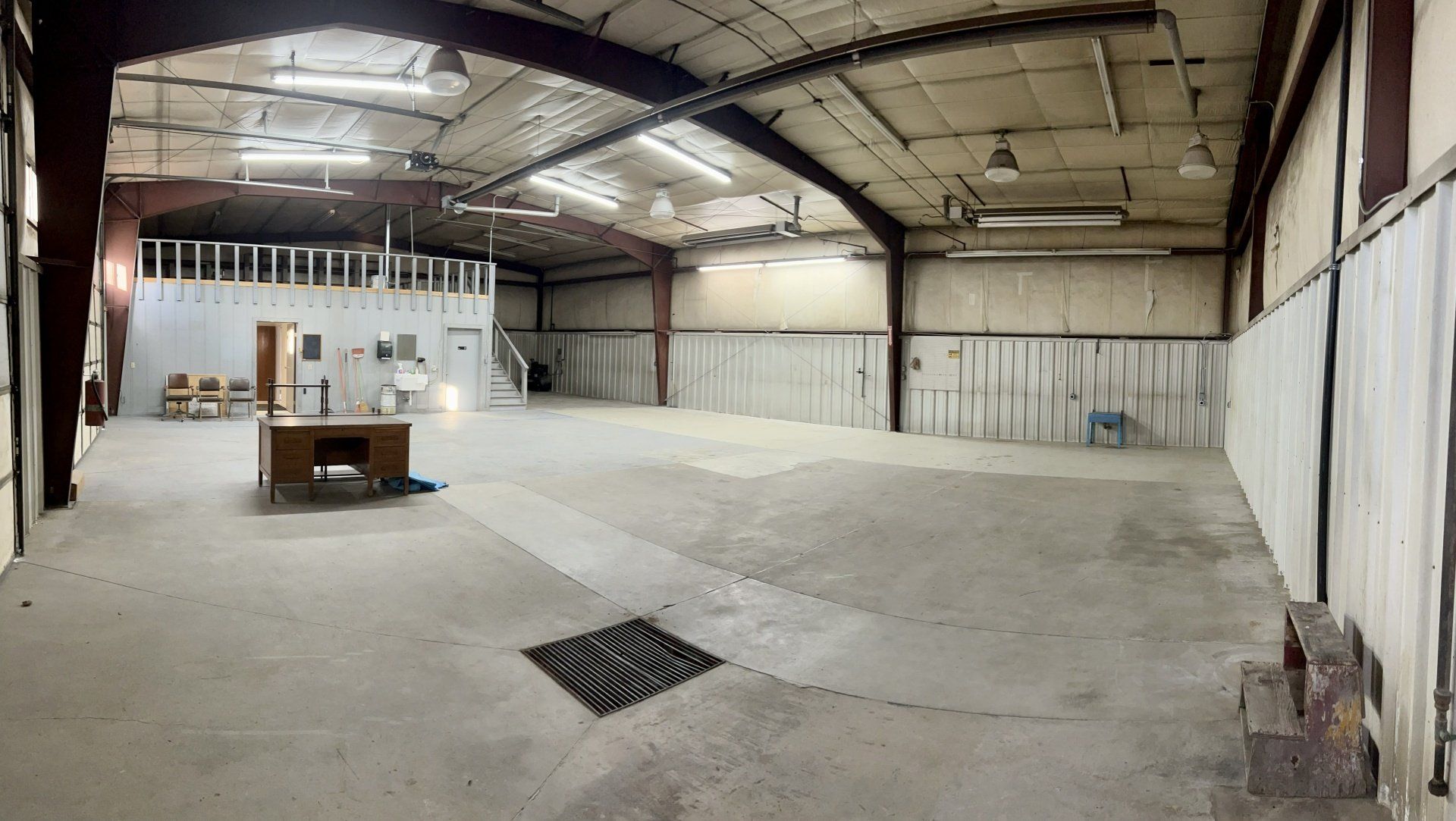 A large empty warehouse with a desk in the middle of it.