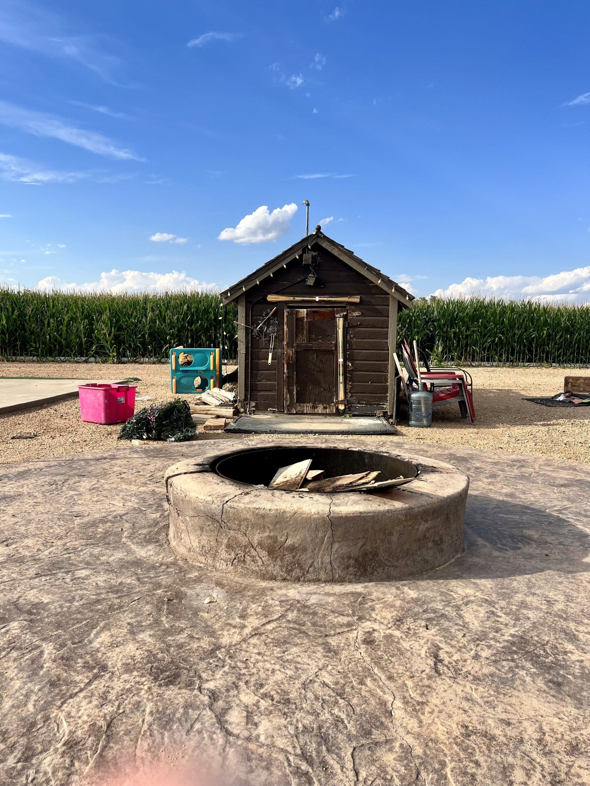 A small wooden shed with a fire pit in front of it.