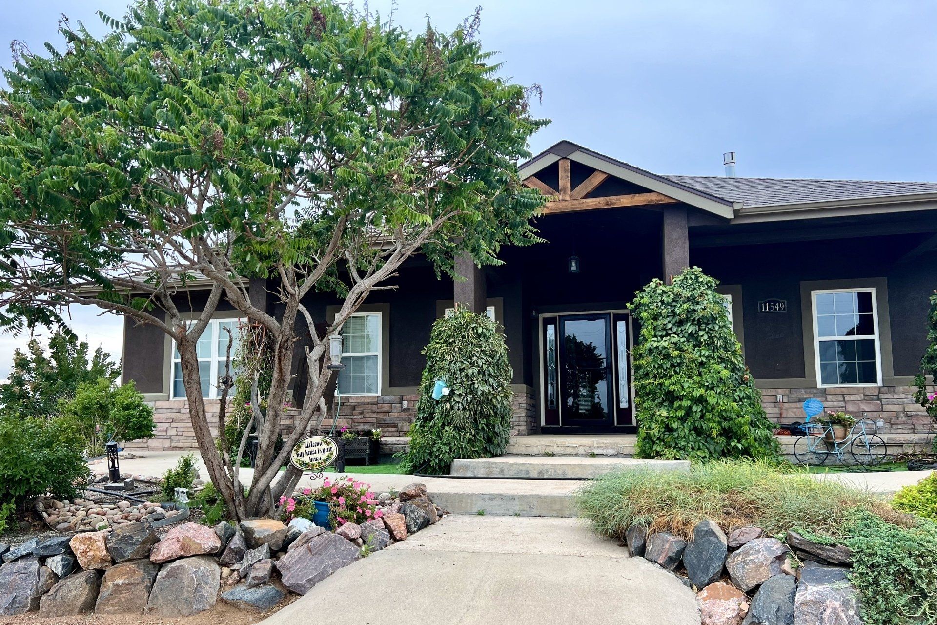 A large house with a tree in front of it and a walkway leading to it.
