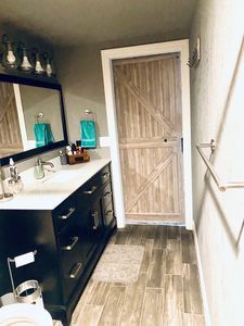A bathroom with a sink , toilet , mirror and barn door.