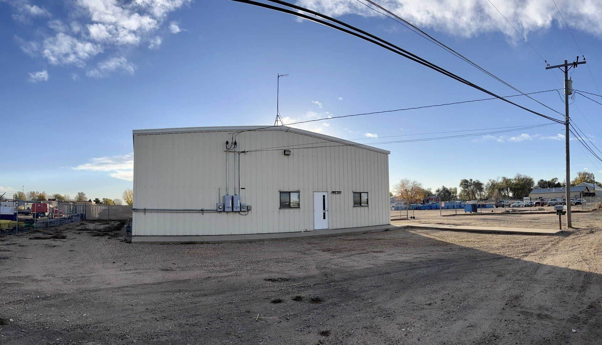 A large white building is sitting in the middle of a dirt field.