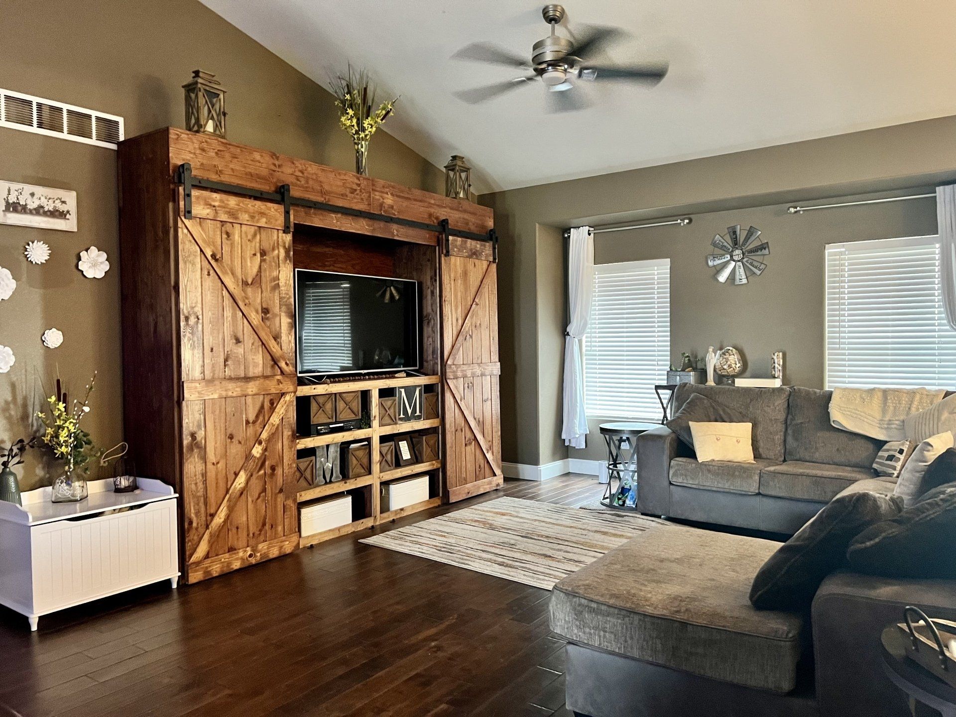 A living room with a couch , television , and sliding barn doors.