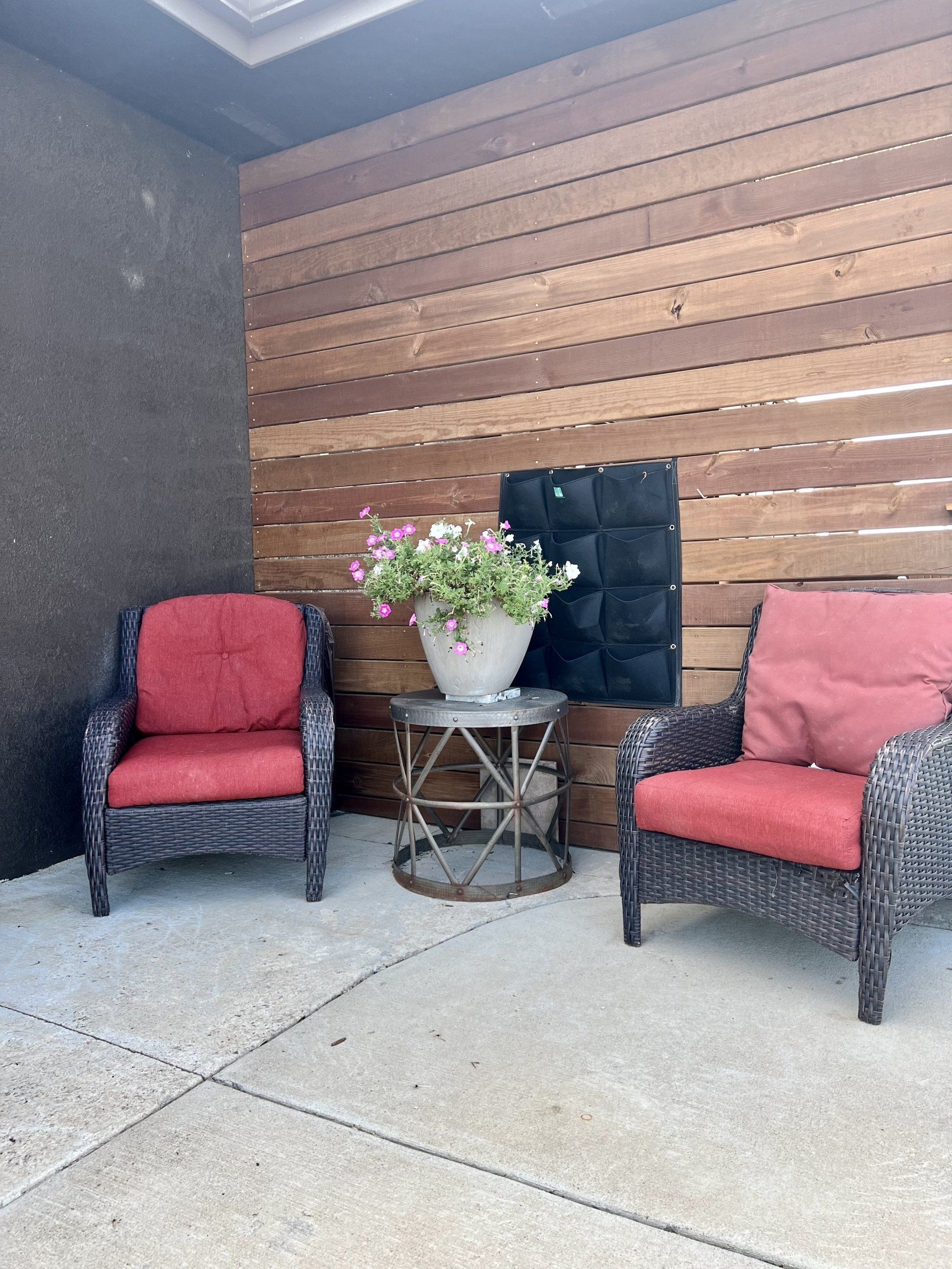A patio with two chairs and a table with flowers on it