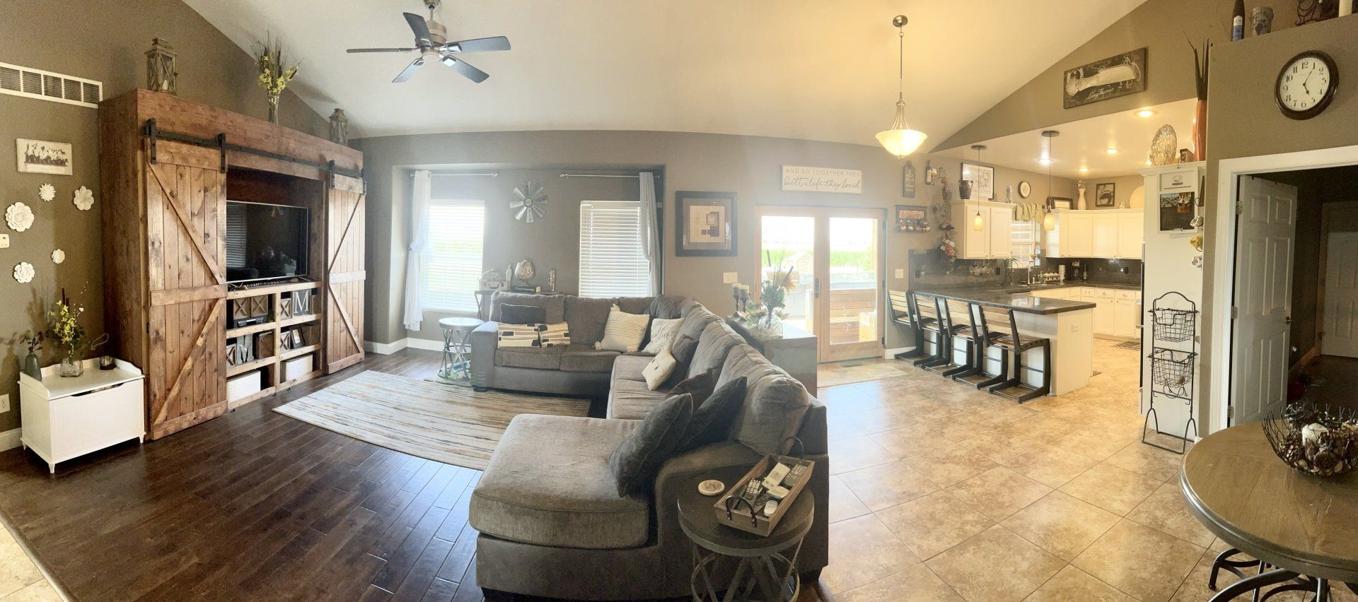 A panoramic view of a living room and kitchen in a house.