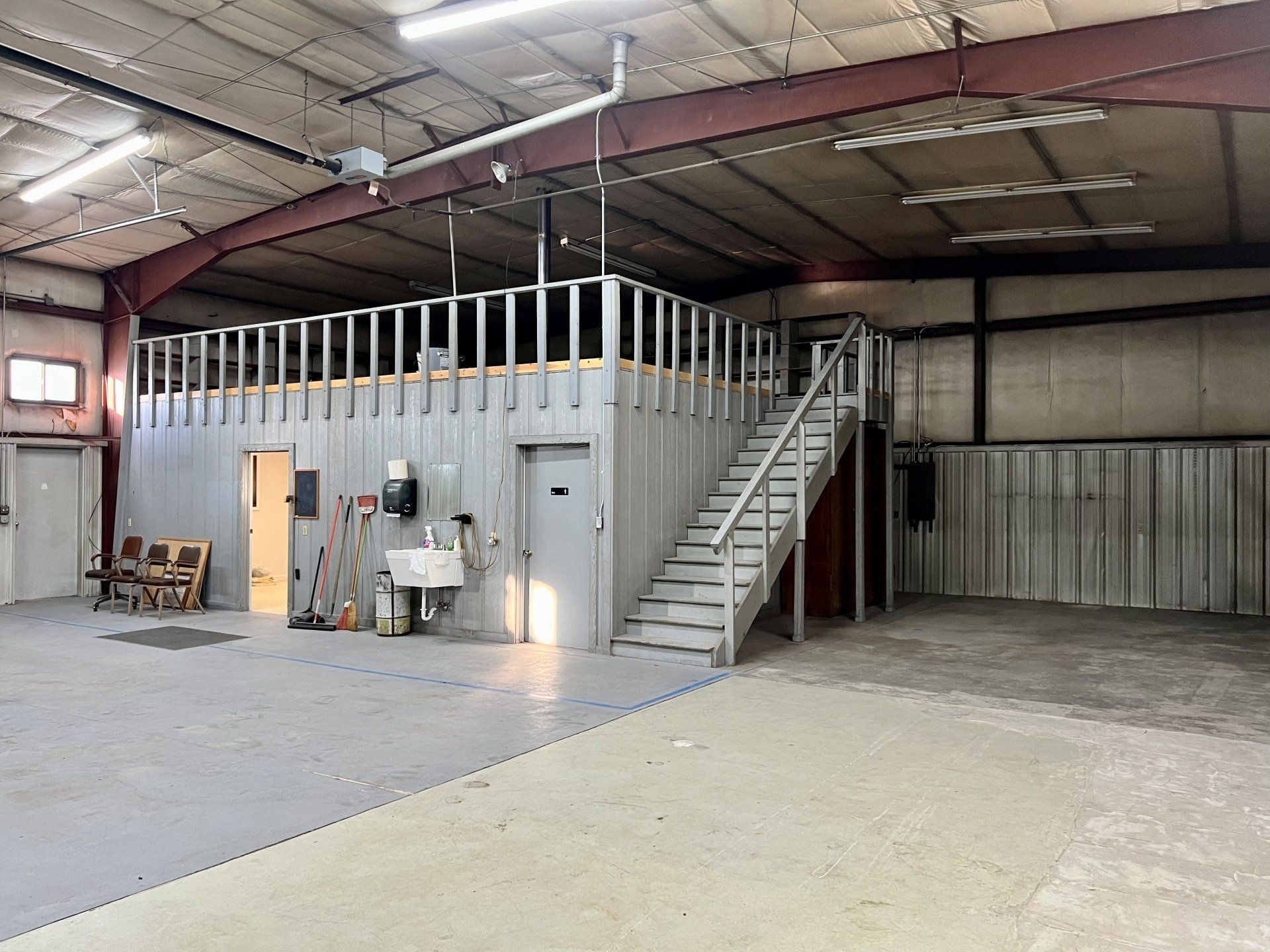 A large empty warehouse with stairs leading up to the second floor.