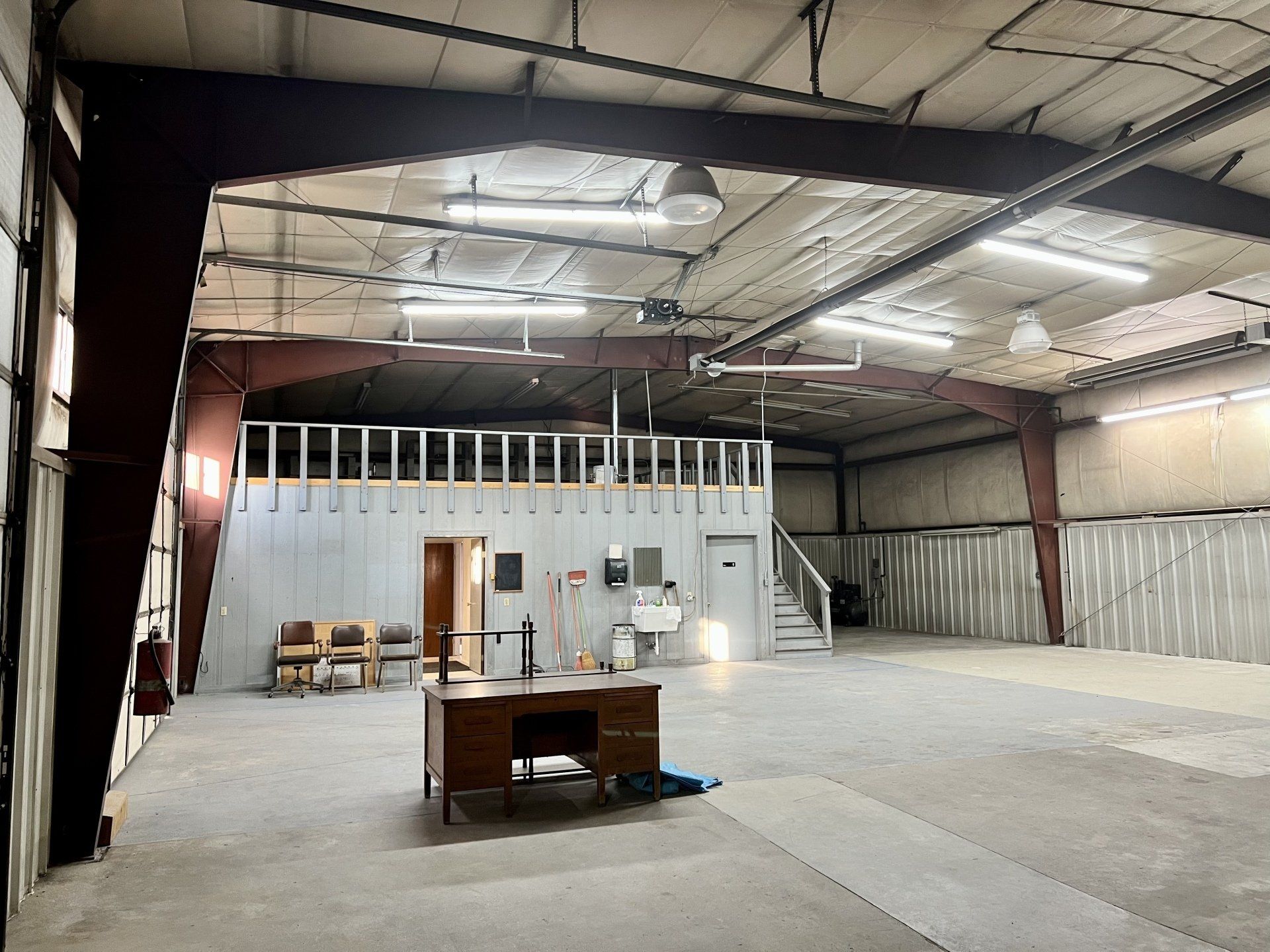 An empty warehouse with a desk and chairs in it