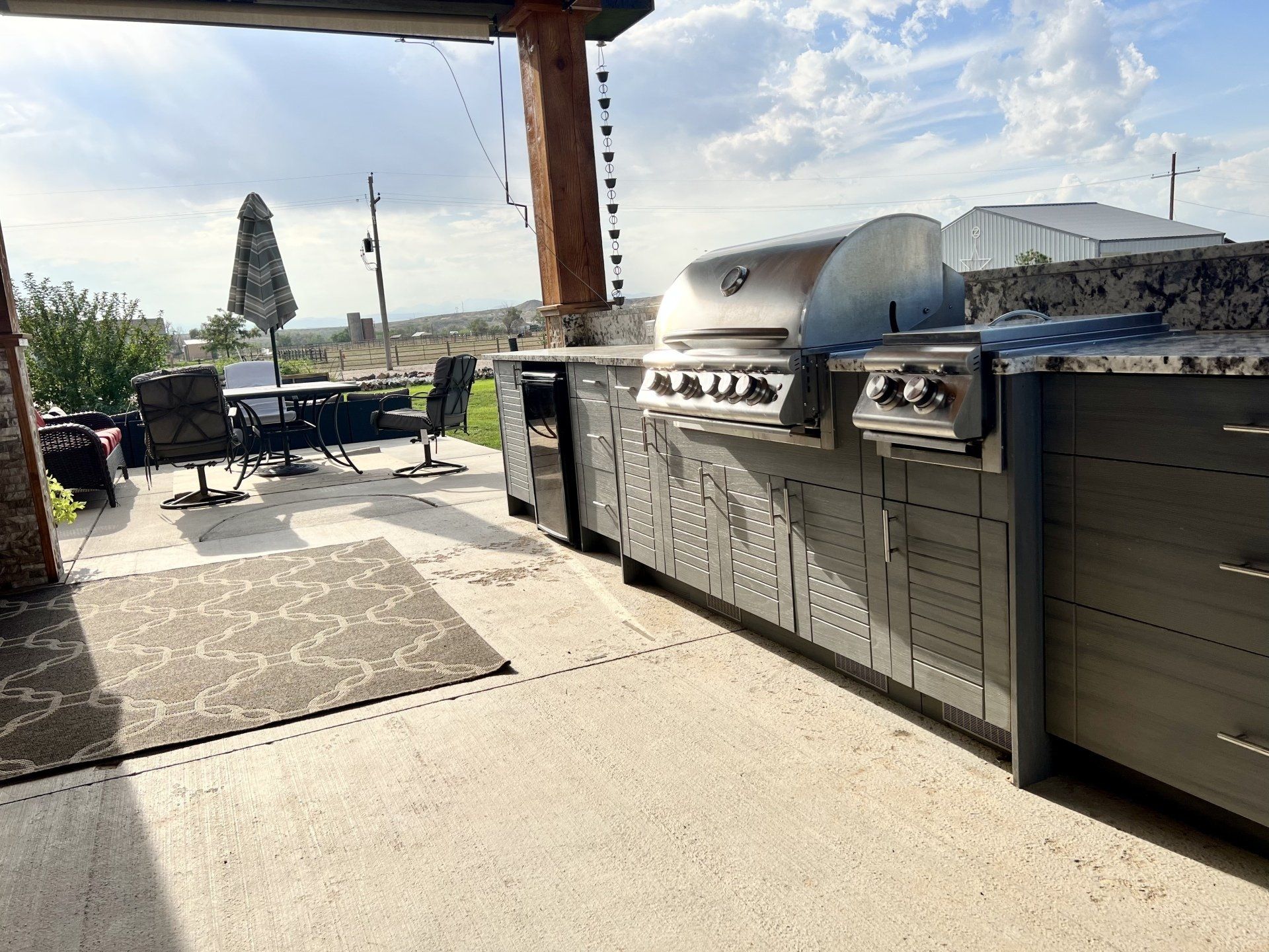 A large outdoor kitchen with a grill and umbrella