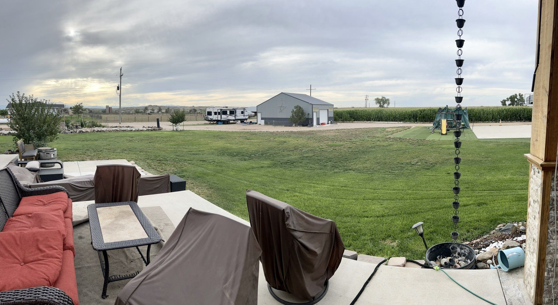 A patio with a couch , table , chairs and a rain chain.