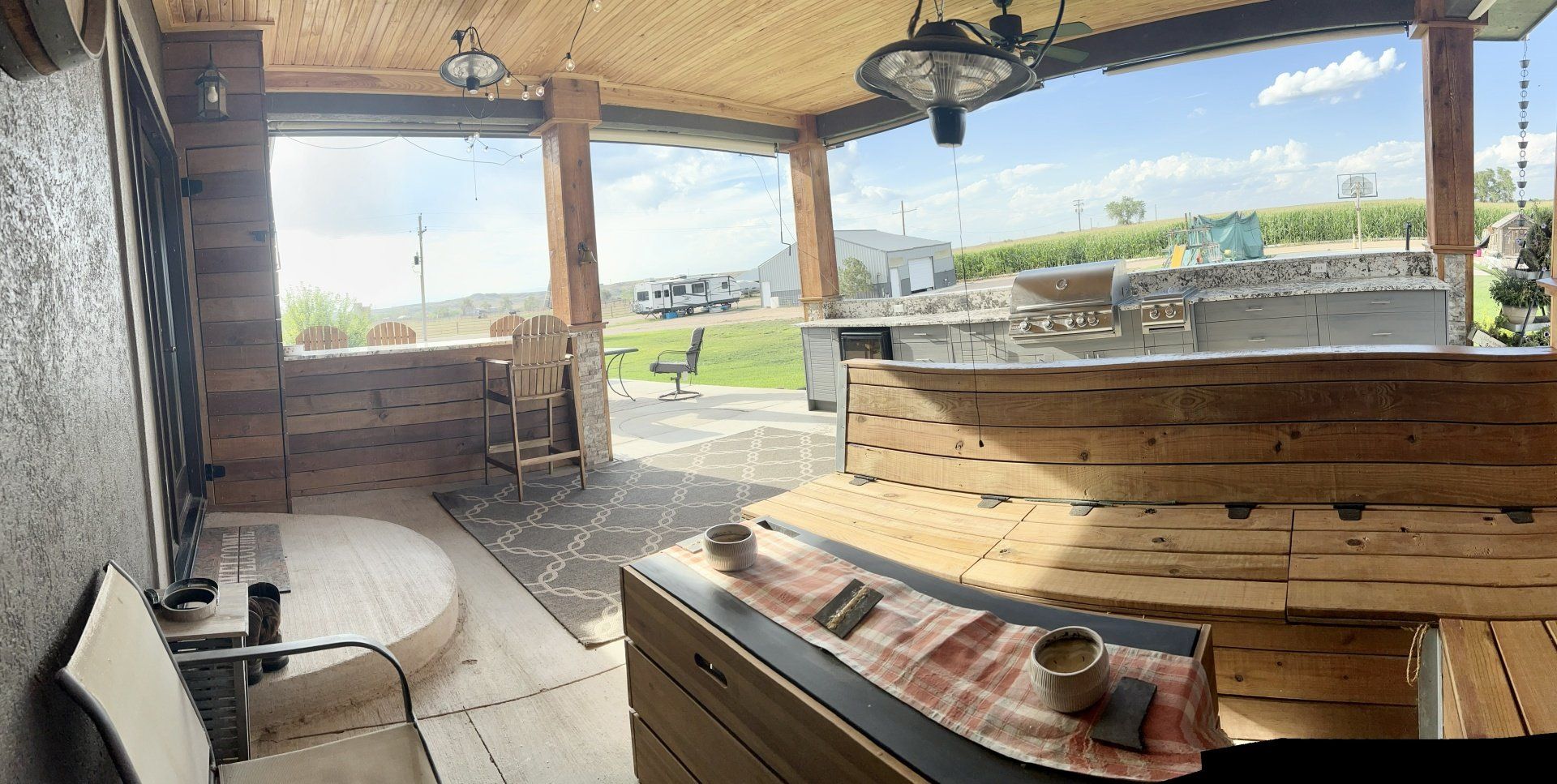 A patio with a wooden table and chairs and a view of a field.