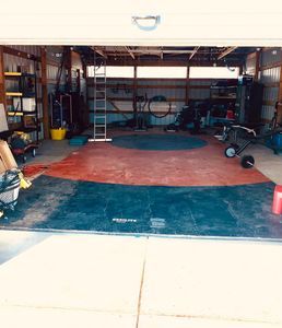 A person is sitting in a wheelbarrow in a garage.