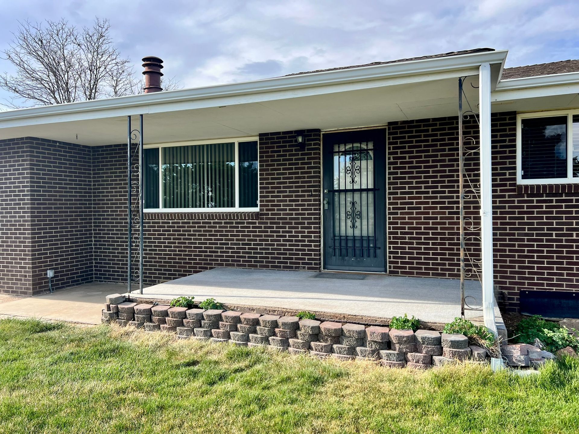 A brick house with a porch and a white roof