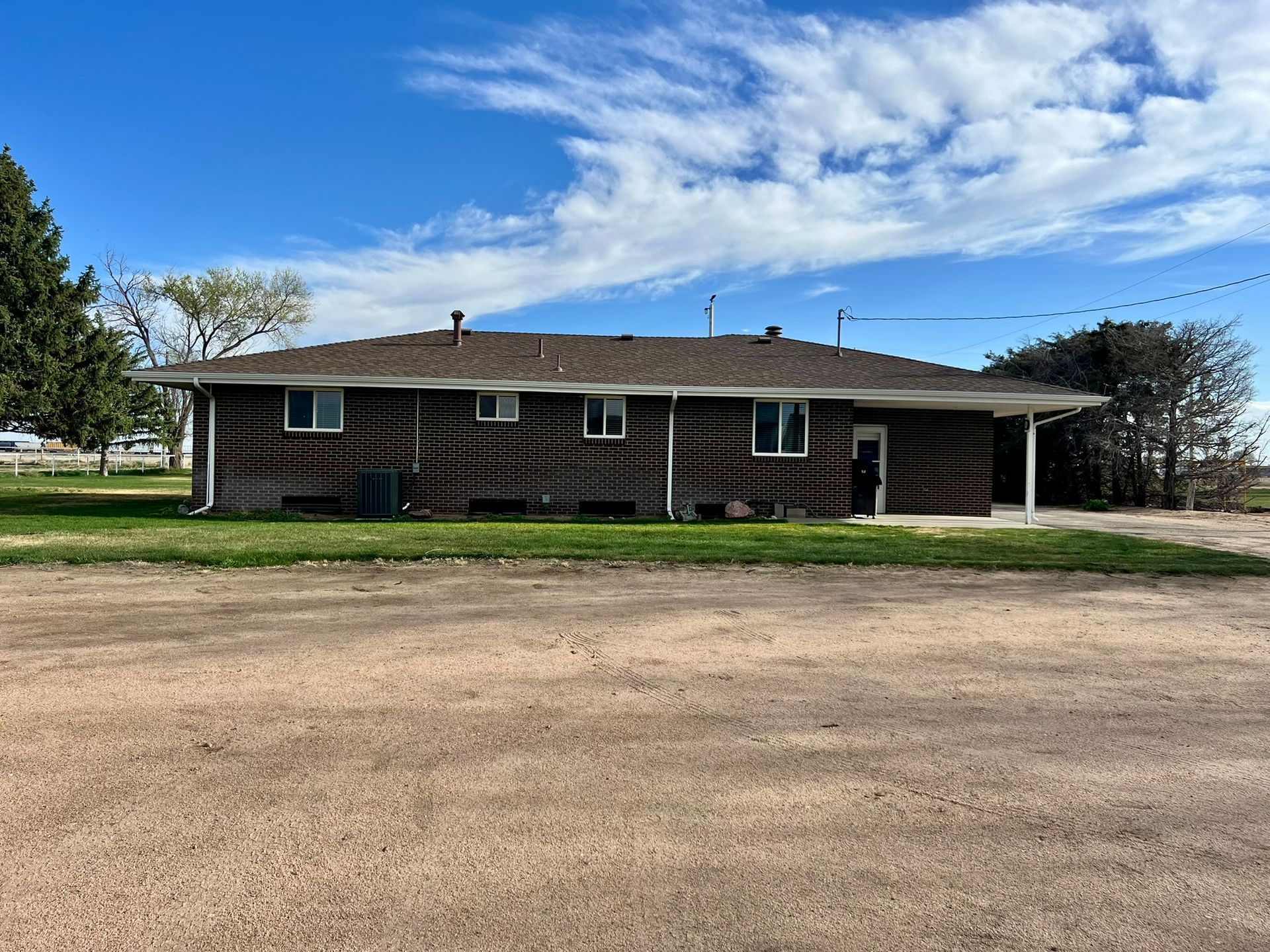 A large log cabin is sitting in the middle of a dirt field.
