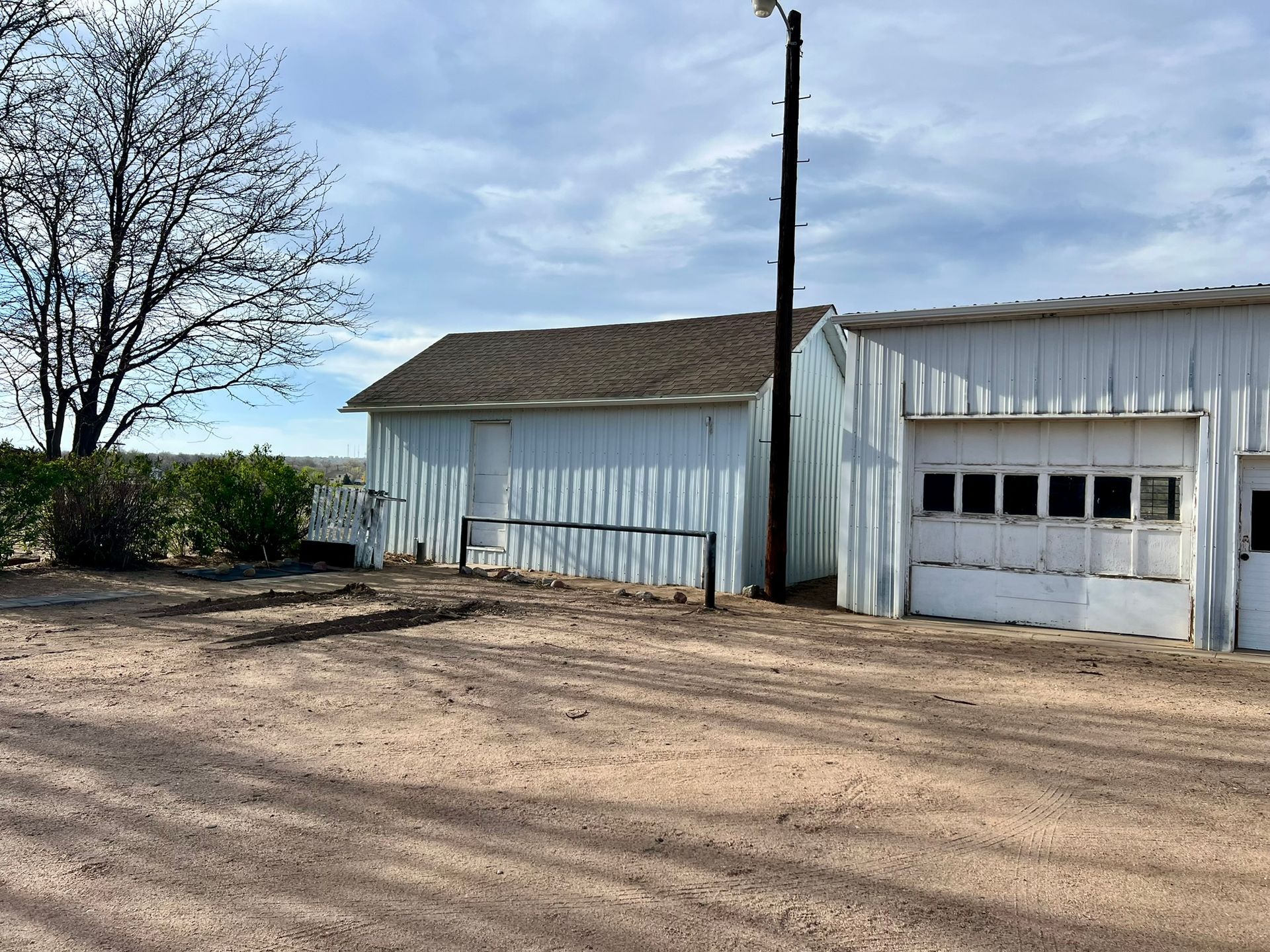A white building with a garage door and a tree in the background