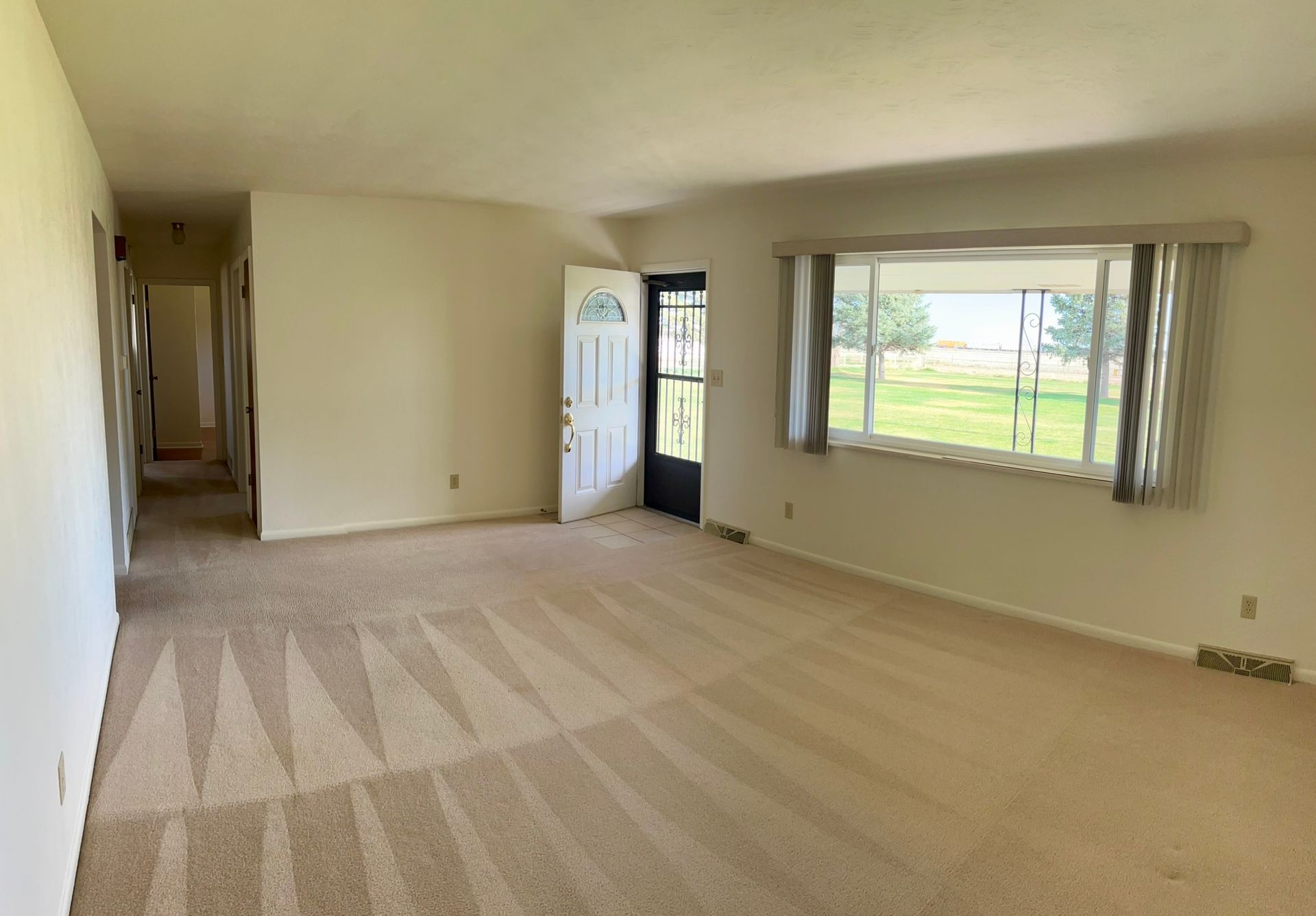 An empty living room with a large window and a door