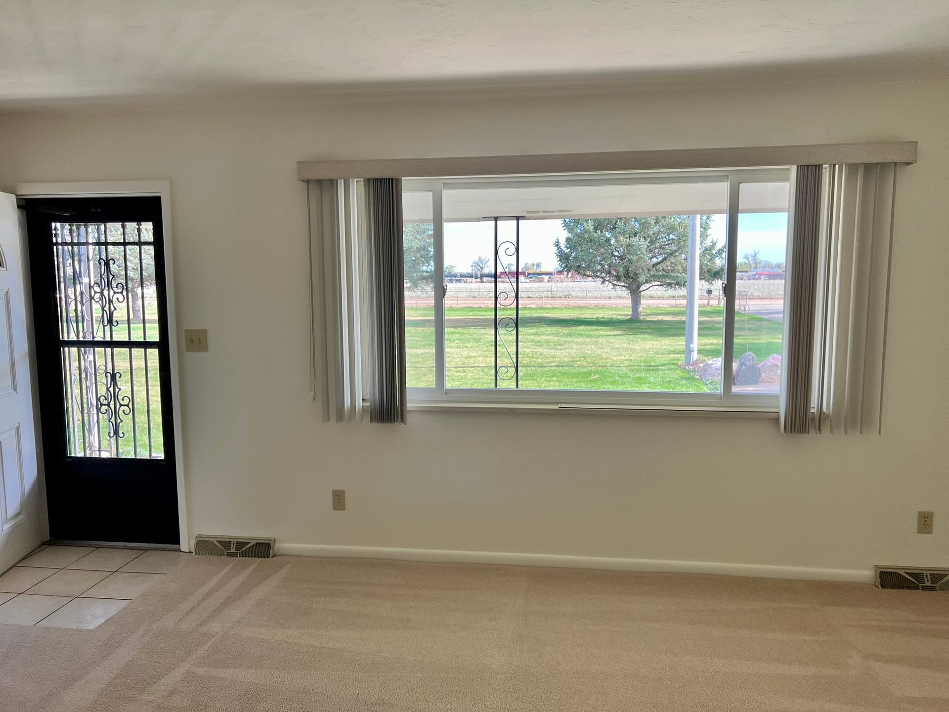 An empty living room with a large window and a door