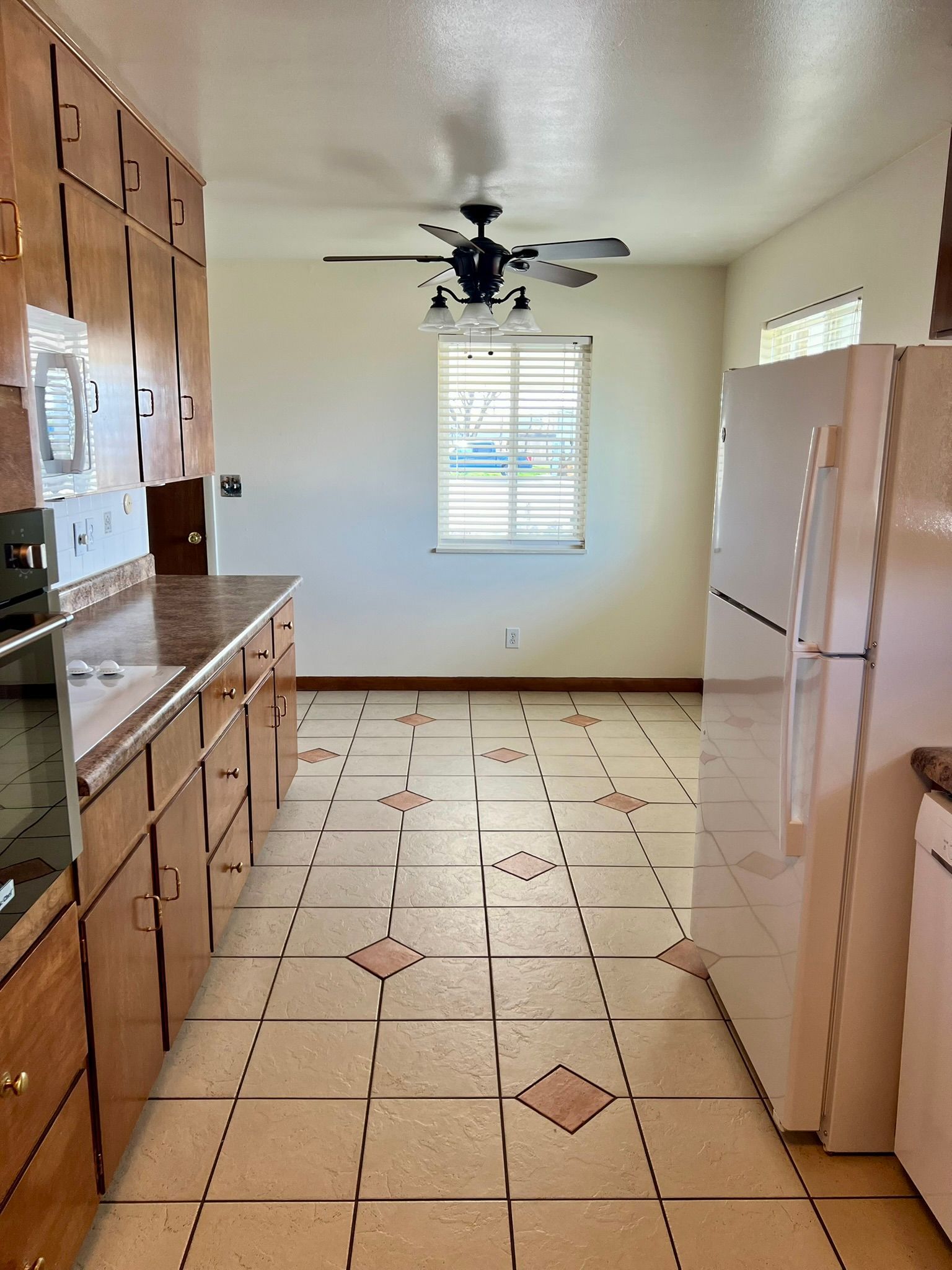 A kitchen with a refrigerator and a ceiling fan