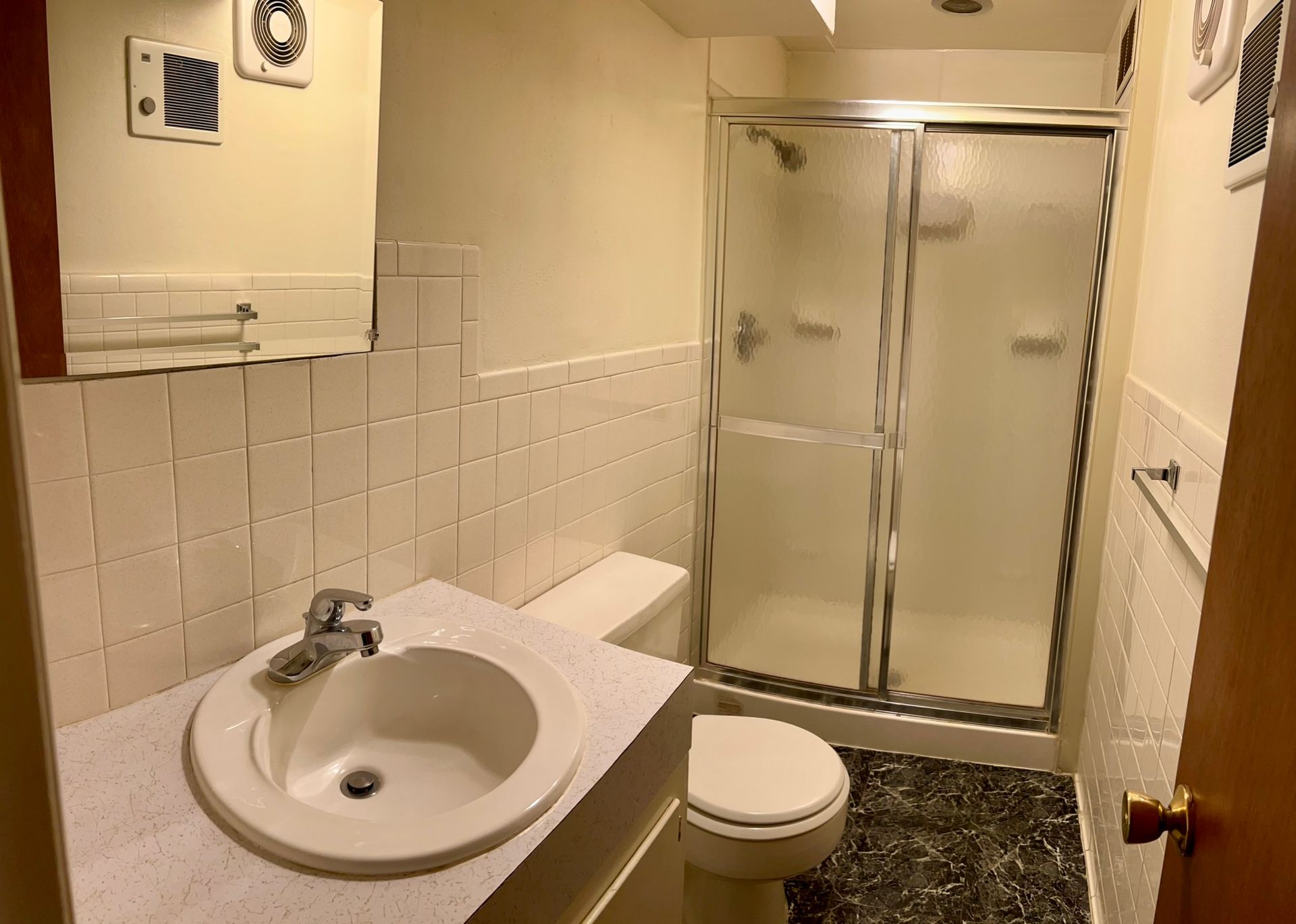 A bathroom with a toilet , sink and shower.
