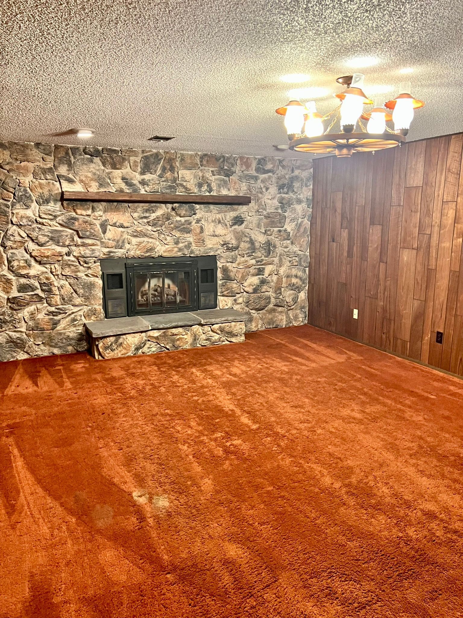An empty living room with a fireplace and a chandelier.