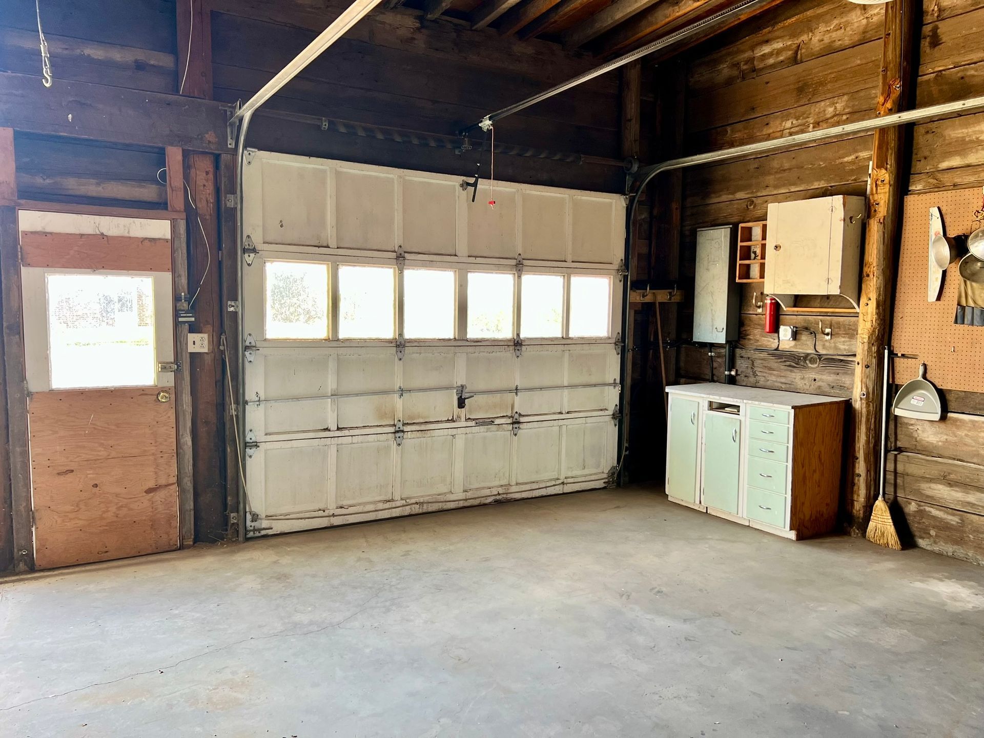 An empty garage with a garage door open and a sink.