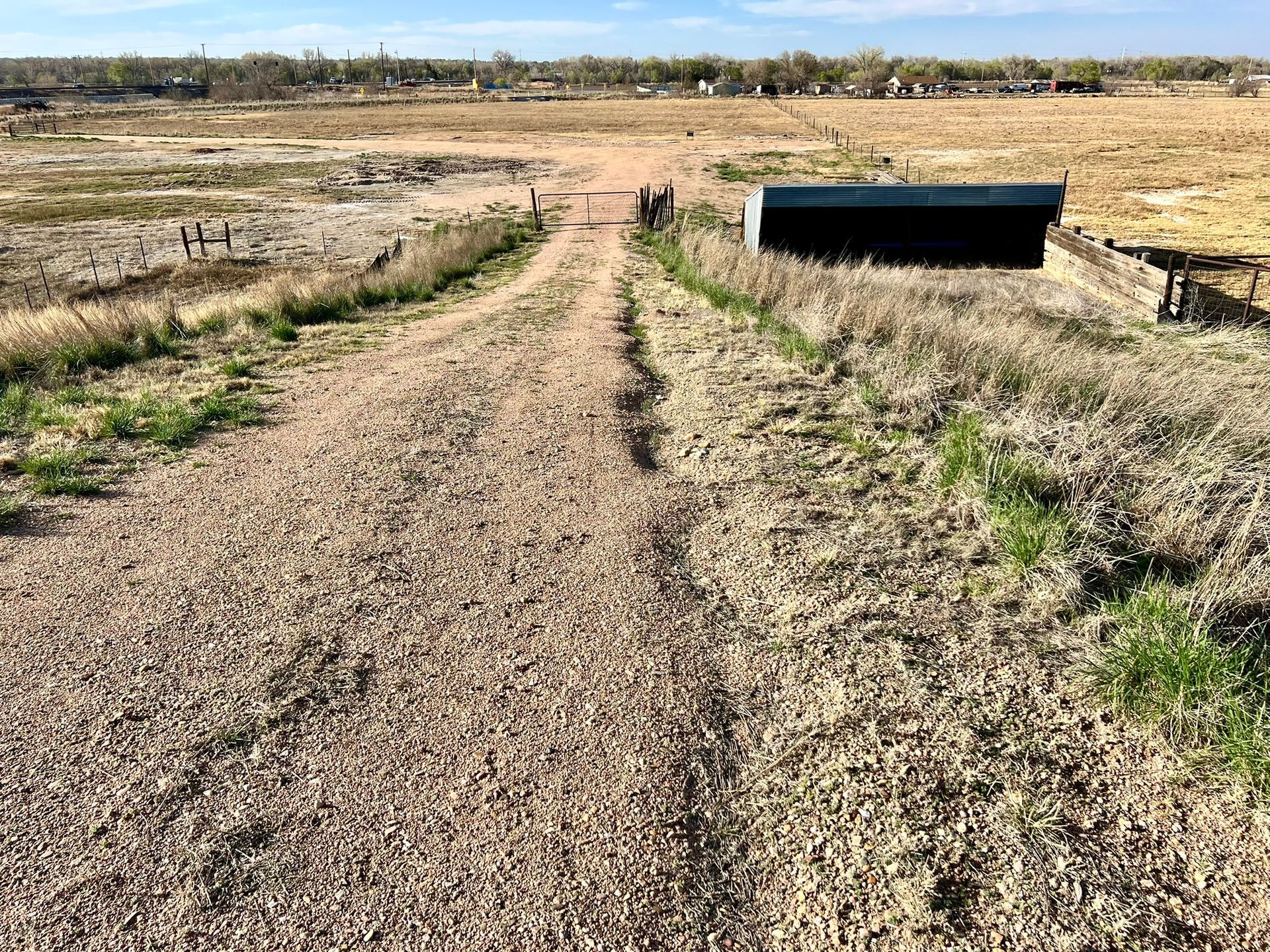 There is a dirt road going through a field.