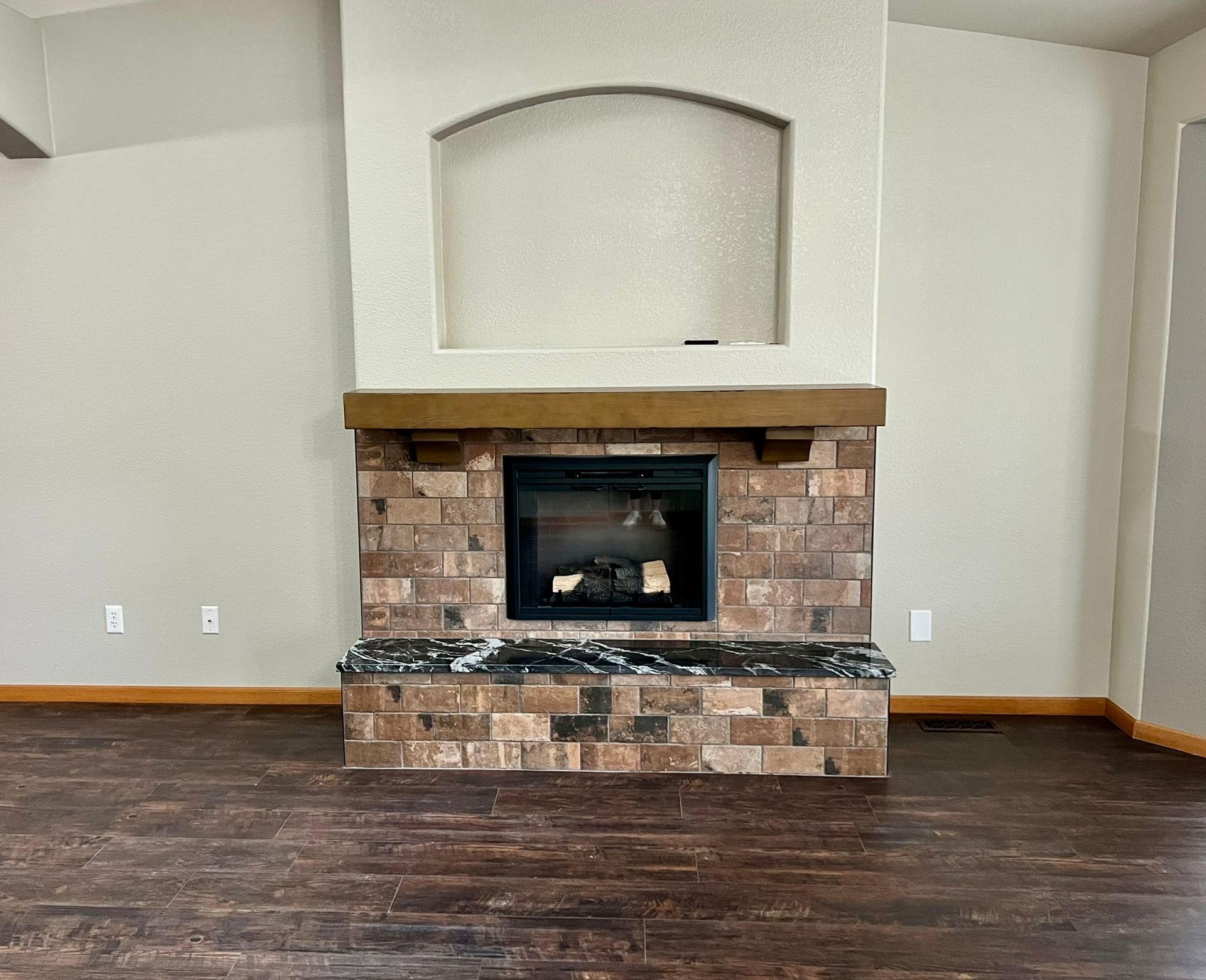 An empty living room with a fireplace in the middle