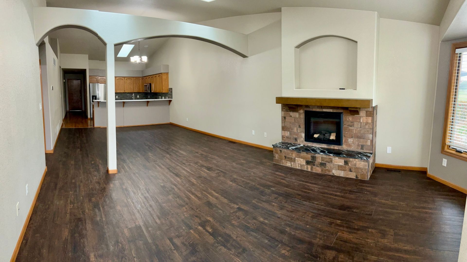An empty living room with hardwood floors and a fireplace.