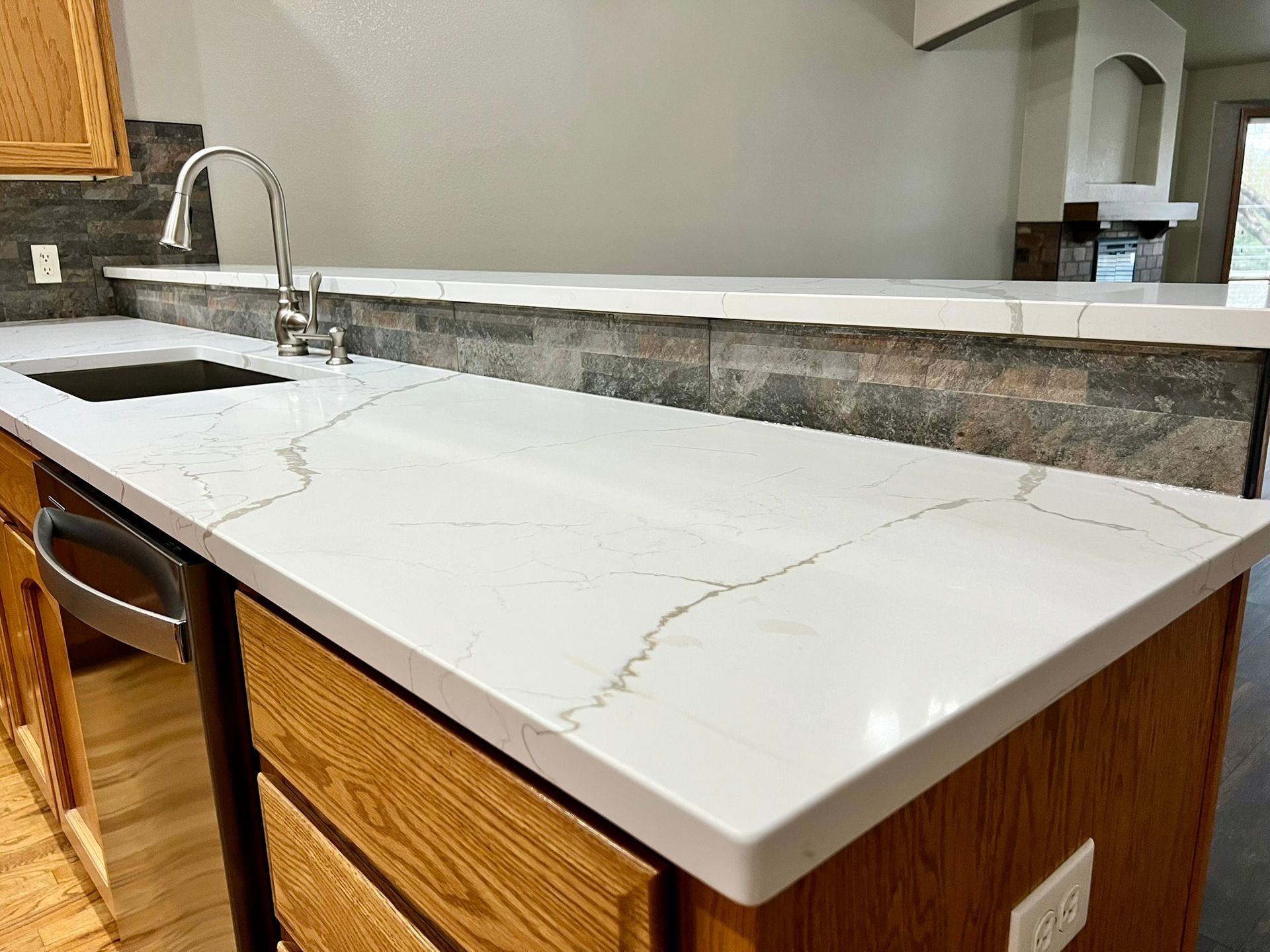 A kitchen with a white counter top , wooden cabinets , and a sink.