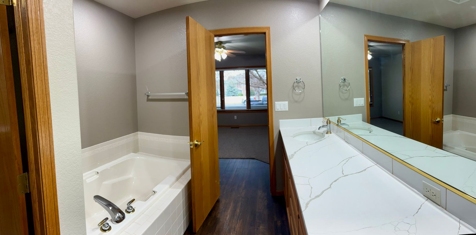 A bathroom with two sinks , a tub , and a large mirror.