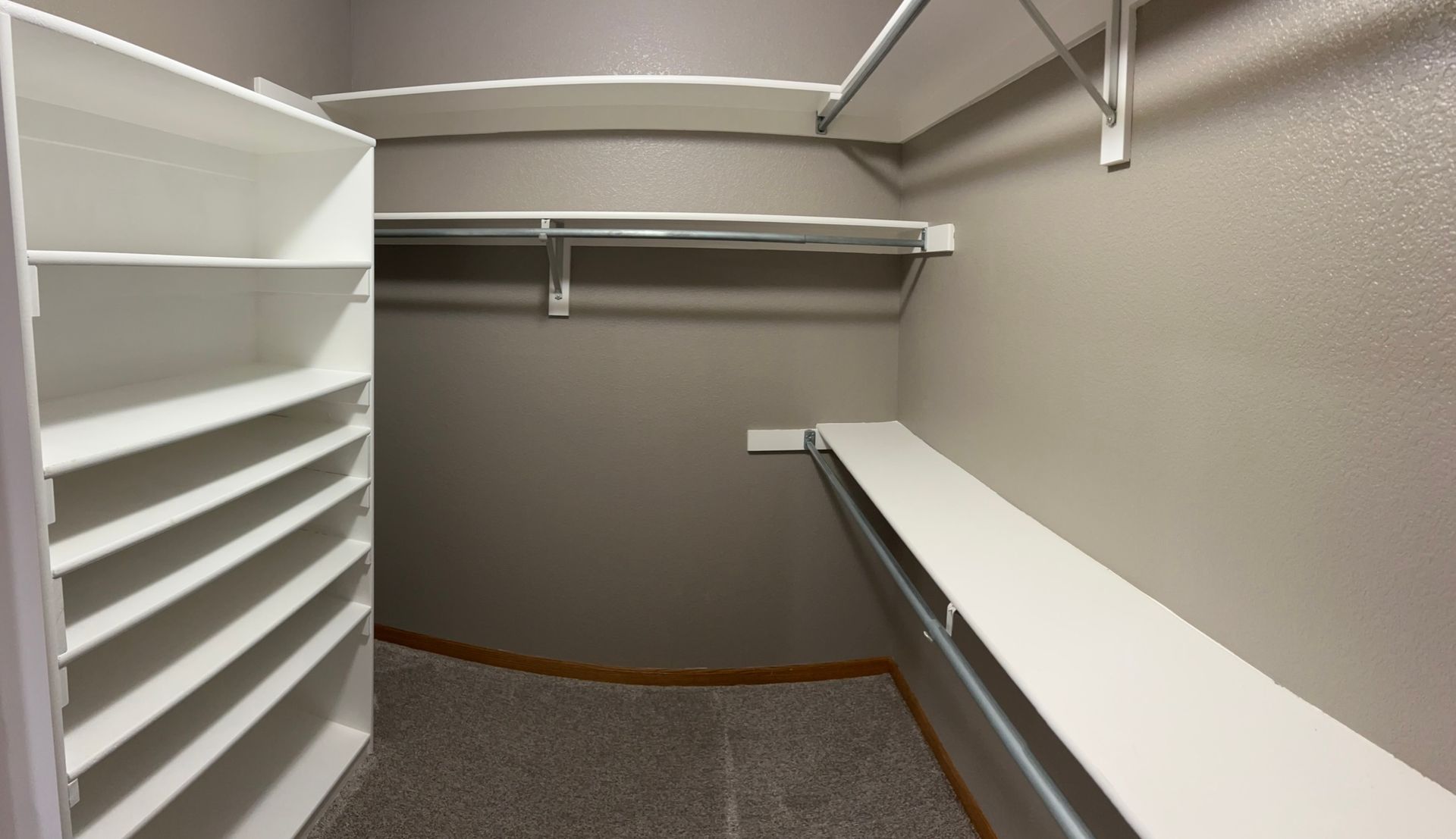 An empty walk in closet with lots of shelves