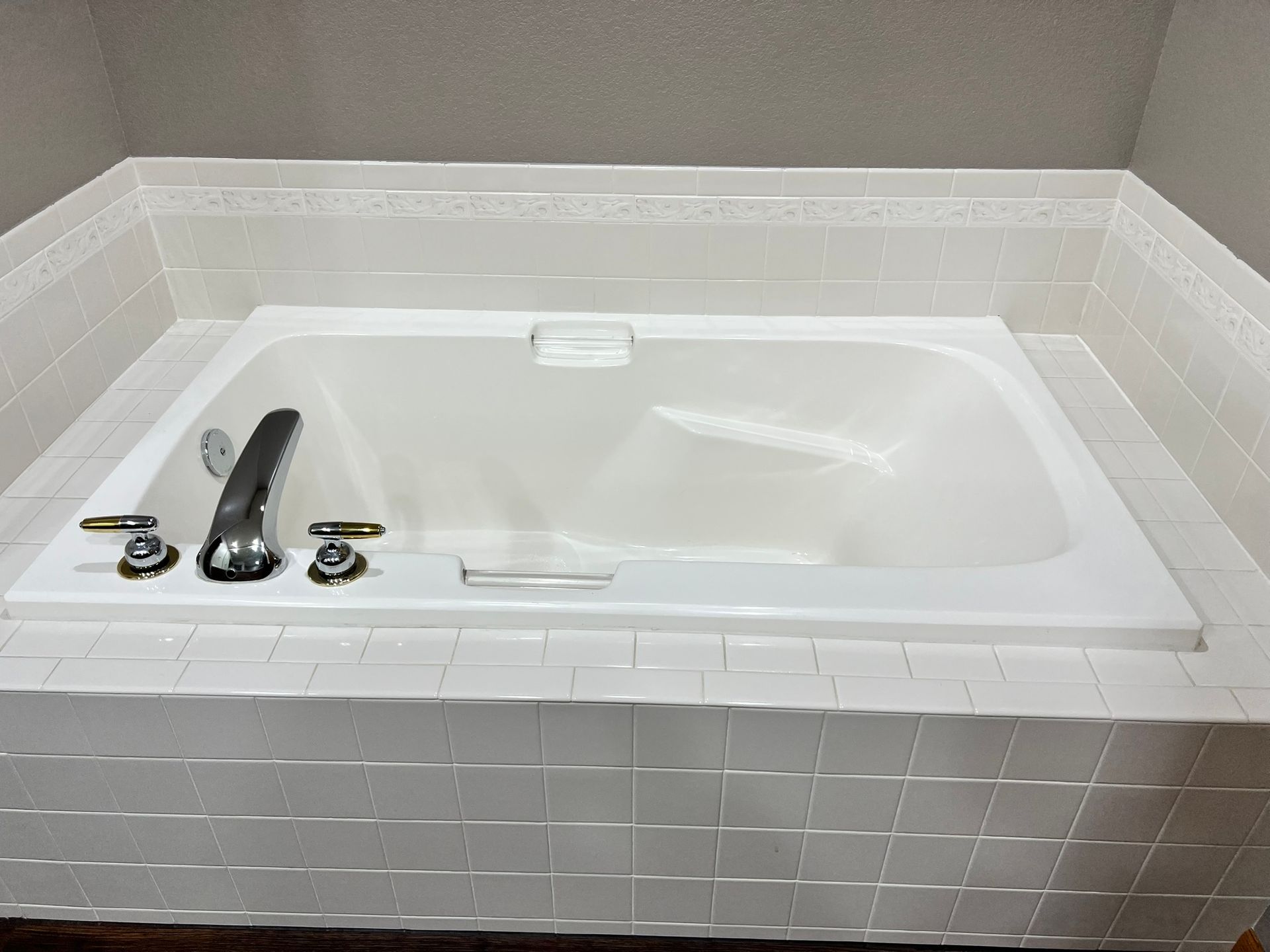 A white bathtub is sitting on top of a white tiled floor in a bathroom.