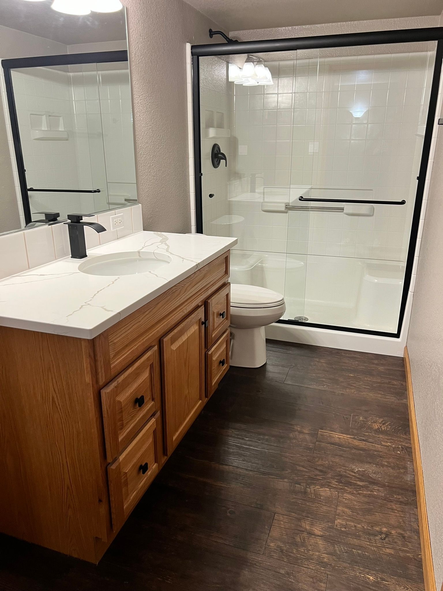 A bathroom with a sink , toilet , shower and mirror.