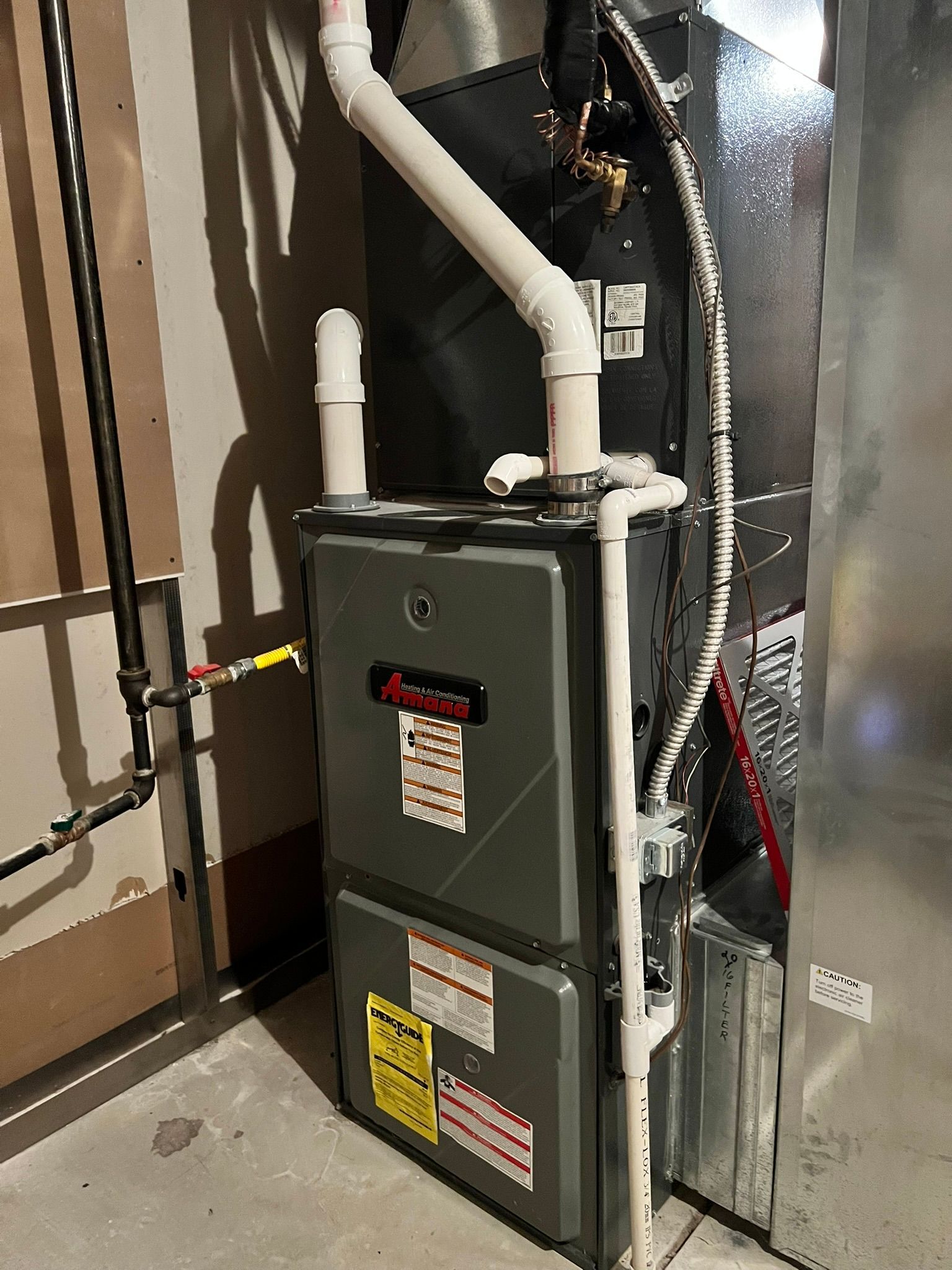 A furnace is sitting in a basement next to a wall.