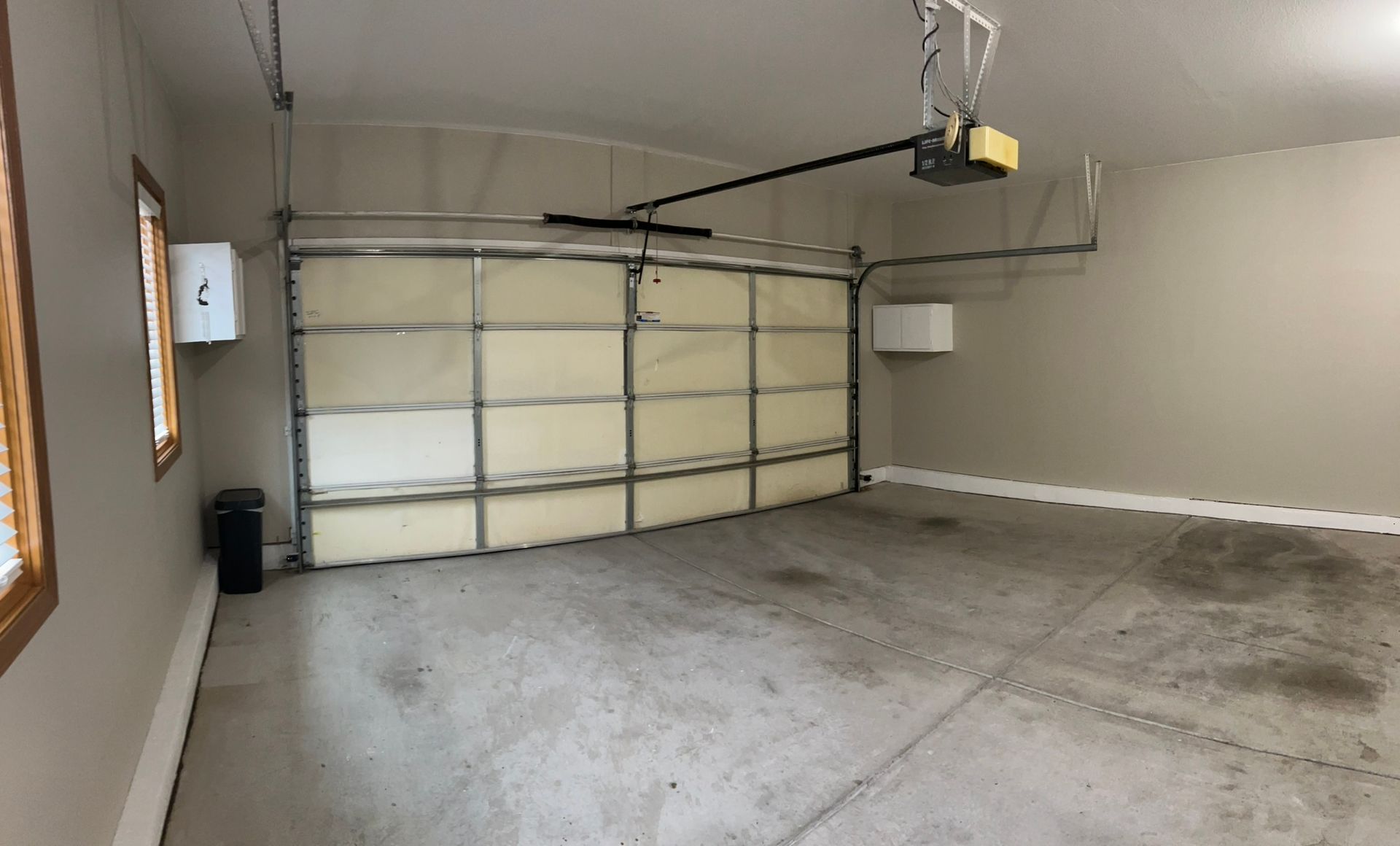 An empty garage with a garage door open and a window.