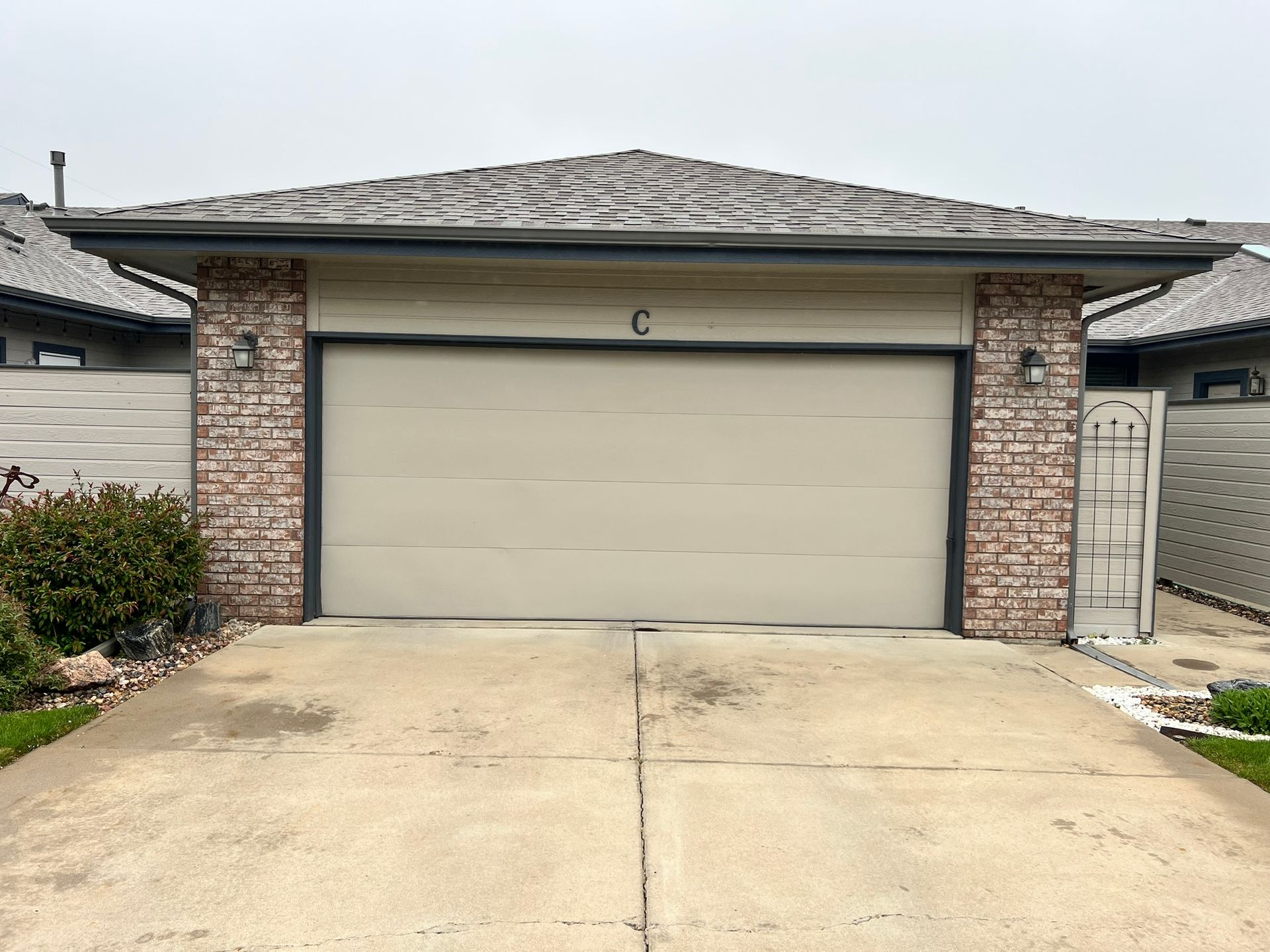 A white garage door is sitting in front of a brick house.