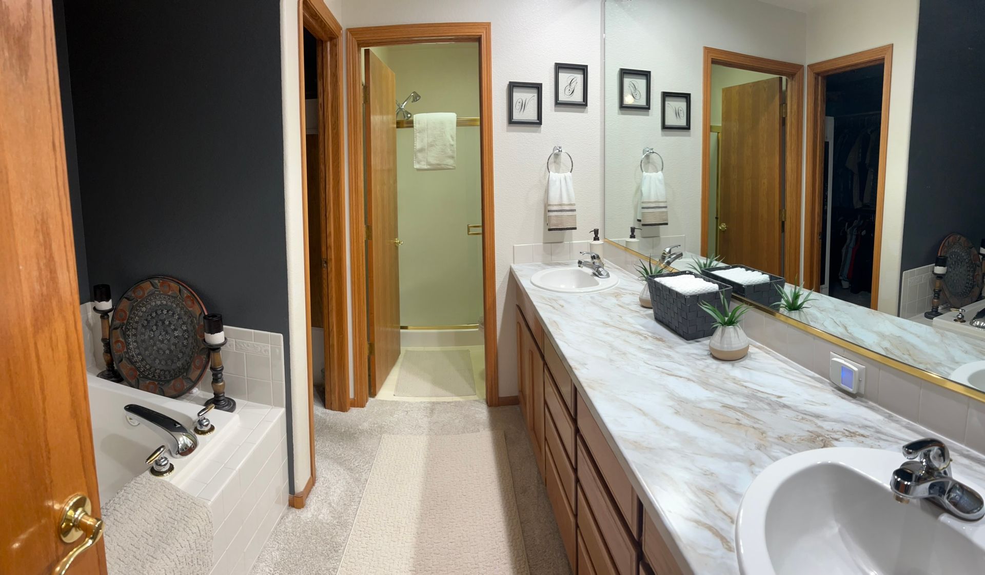 A bathroom with two sinks , a tub , and a large mirror.